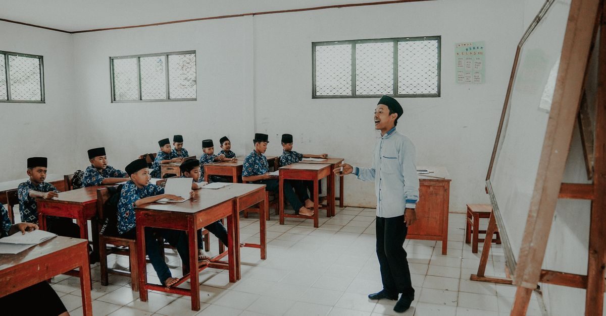 Guru memandu kuis live tanpa HP siswa di kelas dengan proyektor dan lembar jawaban cetak